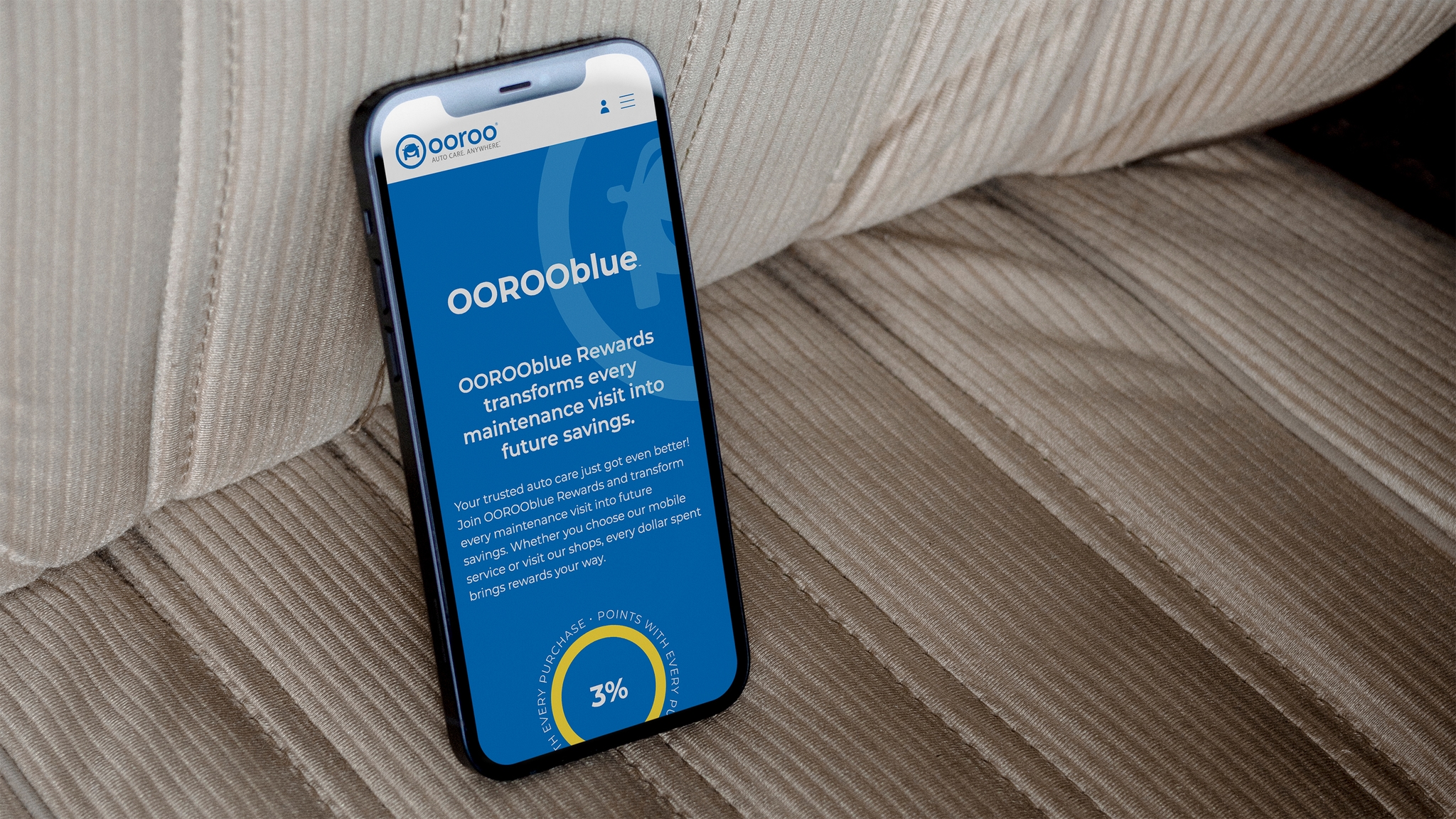 OOROO auto website OOROOBlue rewards page displayed on an iphone that is situated on a drivers car seat made from beige material